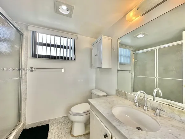 a bathroom with a granite countertop sink a toilet and shower