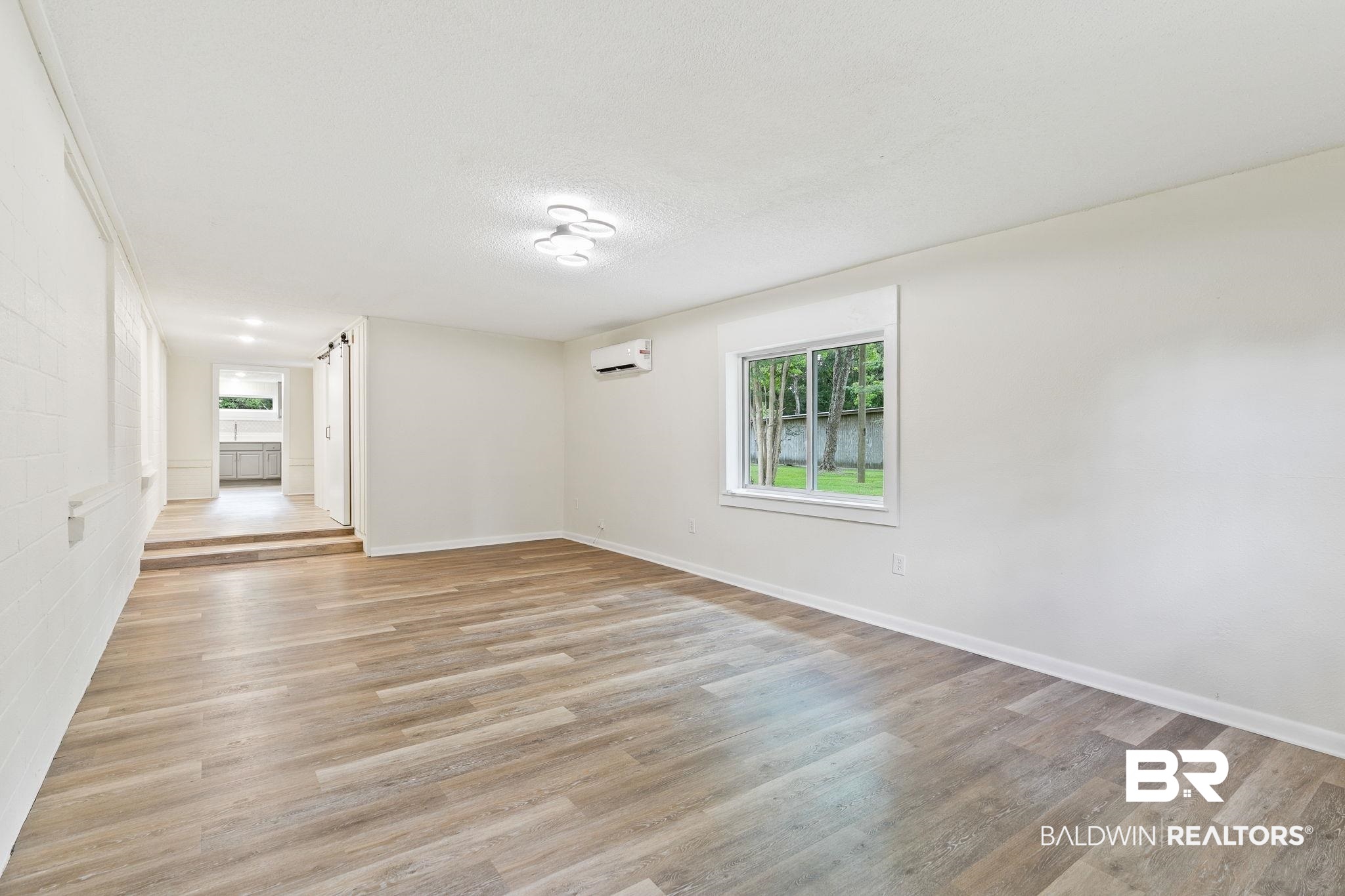 507 Byrne Street Bay Minette, AL 36507 - Photo 5 of 40 Empty room with a wall mounted AC, light hardwood / wood-style floors, and a textured ceiling