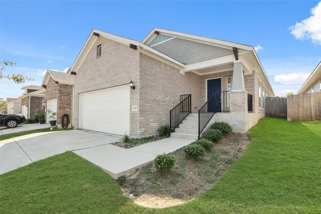 a view of a white house next to a yard and a large tree
