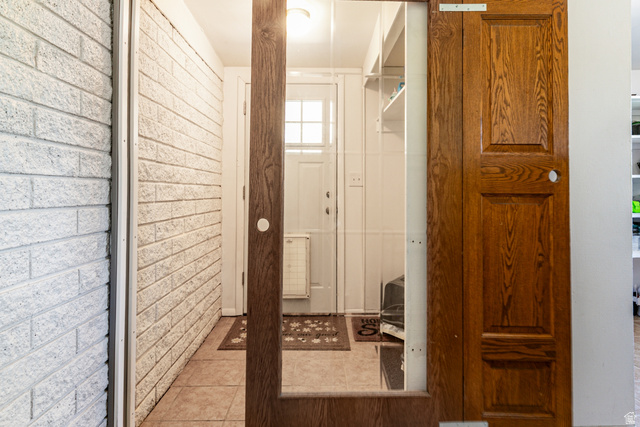 1619 Davis Drive Layton, UT 84041 - Photo 20 of 27 Tiled back entry featuring a wooden sliding barn door, white painted brick wall, and overhead lighting
