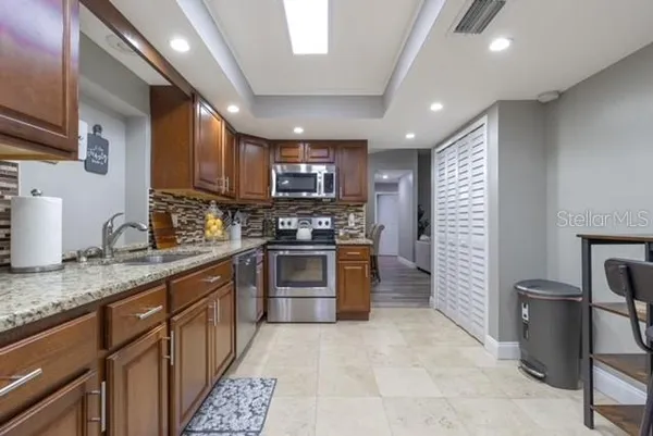 a kitchen with stainless steel appliances granite countertop wooden cabinets a stove top oven a sink and dishwasher