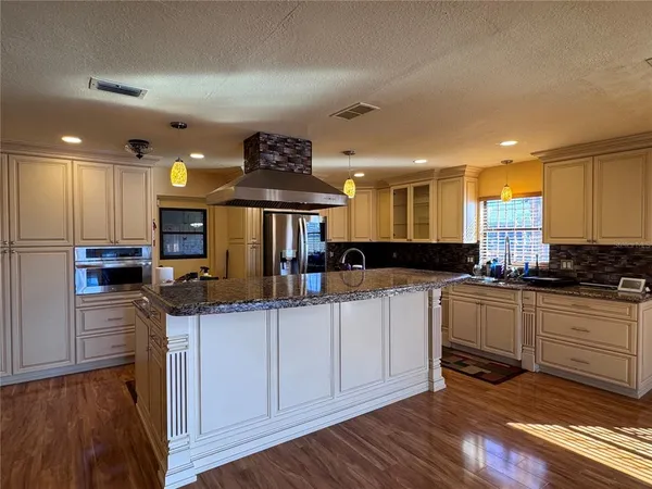 a kitchen with kitchen island granite countertop wooden floors and stainless steel appliances