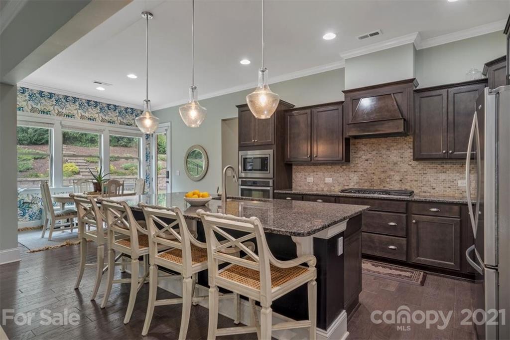 1526 Afton Way Fort Mill, SC 29708 - Photo 14 of 48 a kitchen with stainless steel appliances kitchen island granite countertop a stove a sink a dining table and chairs with wooden floor