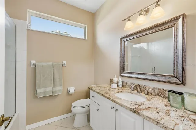 a bathroom with a granite countertop sink mirror vanity and toilet