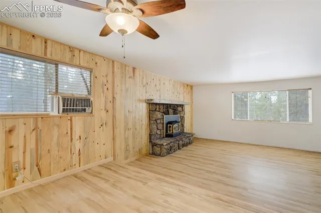 an empty room with wooden floor fireplace and windows