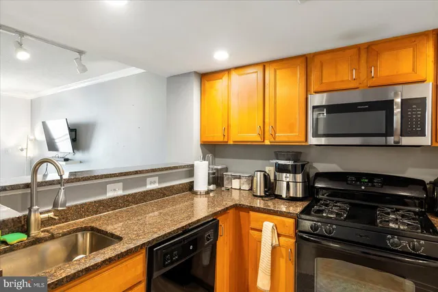a kitchen with granite countertop a sink stainless steel appliances and cabinets