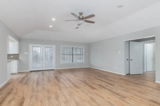 a view of an empty room with a window and wooden floor