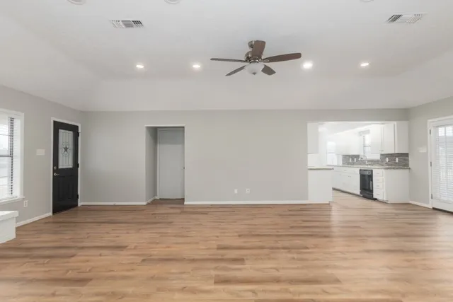 a view of empty room with wooden floor and window