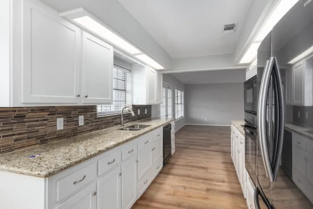 a kitchen with granite countertop a sink and refrigerator