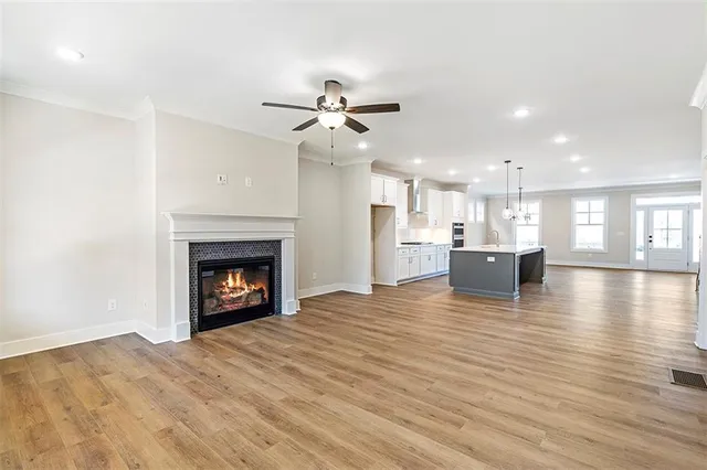 a view of a kitchen and an empty room with wooden floor