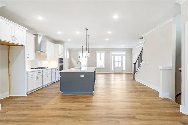 a kitchen with stainless steel appliances granite countertop a refrigerator a sink dishwasher a stove and white countertops with wooden floor