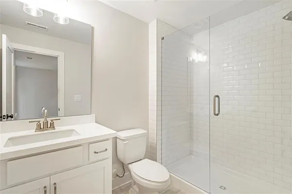 a bathroom with a shower sink vanity mirror and toilet