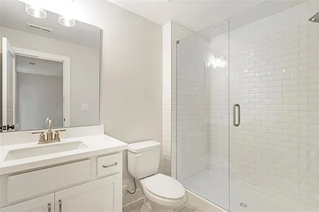 a bathroom with a shower sink vanity mirror and toilet