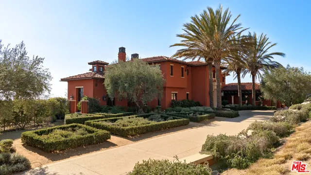 a front view of a house with a yard and palm trees