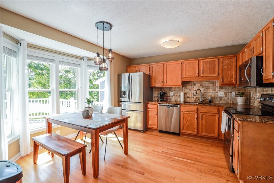 11400 Bailey Mountain Trail Midlothian, VA 23112 - Photo 28 of 41 a kitchen with stainless steel appliances granite countertop wooden floors stove refrigerator dining table and chairs