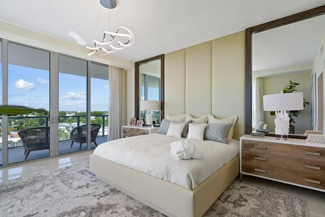a bedroom with a bed a large window and chandelier