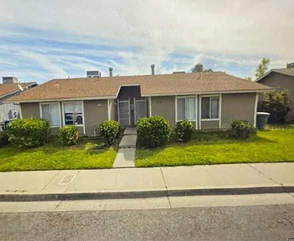 a front view of a house with a yard and potted plants
