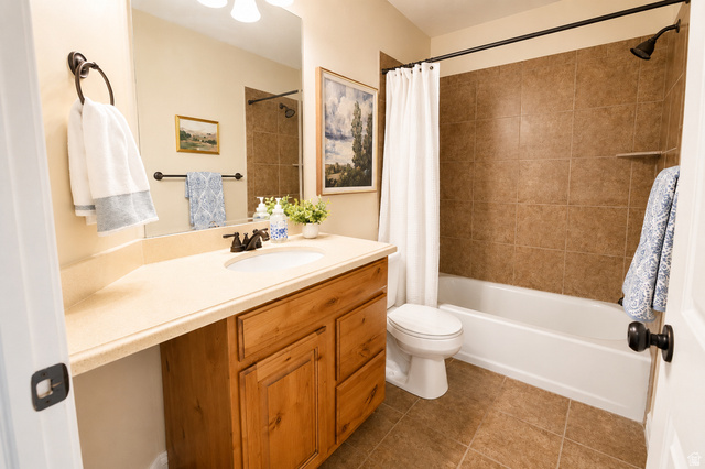 896 Cres Drive South Mapleton, UT 84664 - Photo 24 of 32 Full bathroom featuring a single vanity with wood cabinetry and a light-toned countertop, a built-in tub with tile surround, and coordinating tile flooring