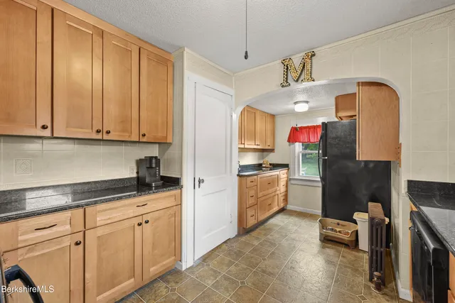 a kitchen with stainless steel appliances granite countertop a refrigerator a stove a sink dishwasher and white cabinets with wooden floor