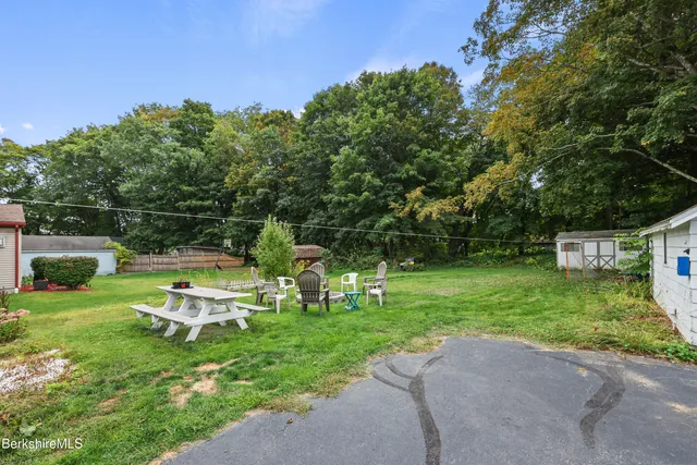 a view of a house with a yard and a large tree
