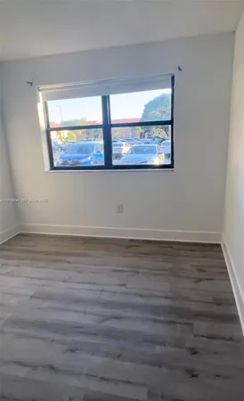 a view of an empty room with wooden floor and window