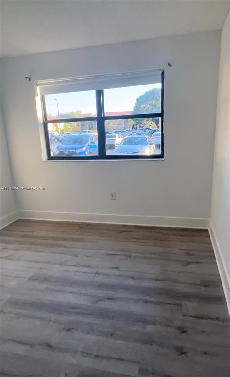 15640 Southwest 80th Street, Unit G103 Miami, FL 33193 - Photo 6 of 11 a view of an empty room with wooden floor and window
