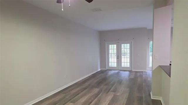 a view of an empty room with wooden floor and a window