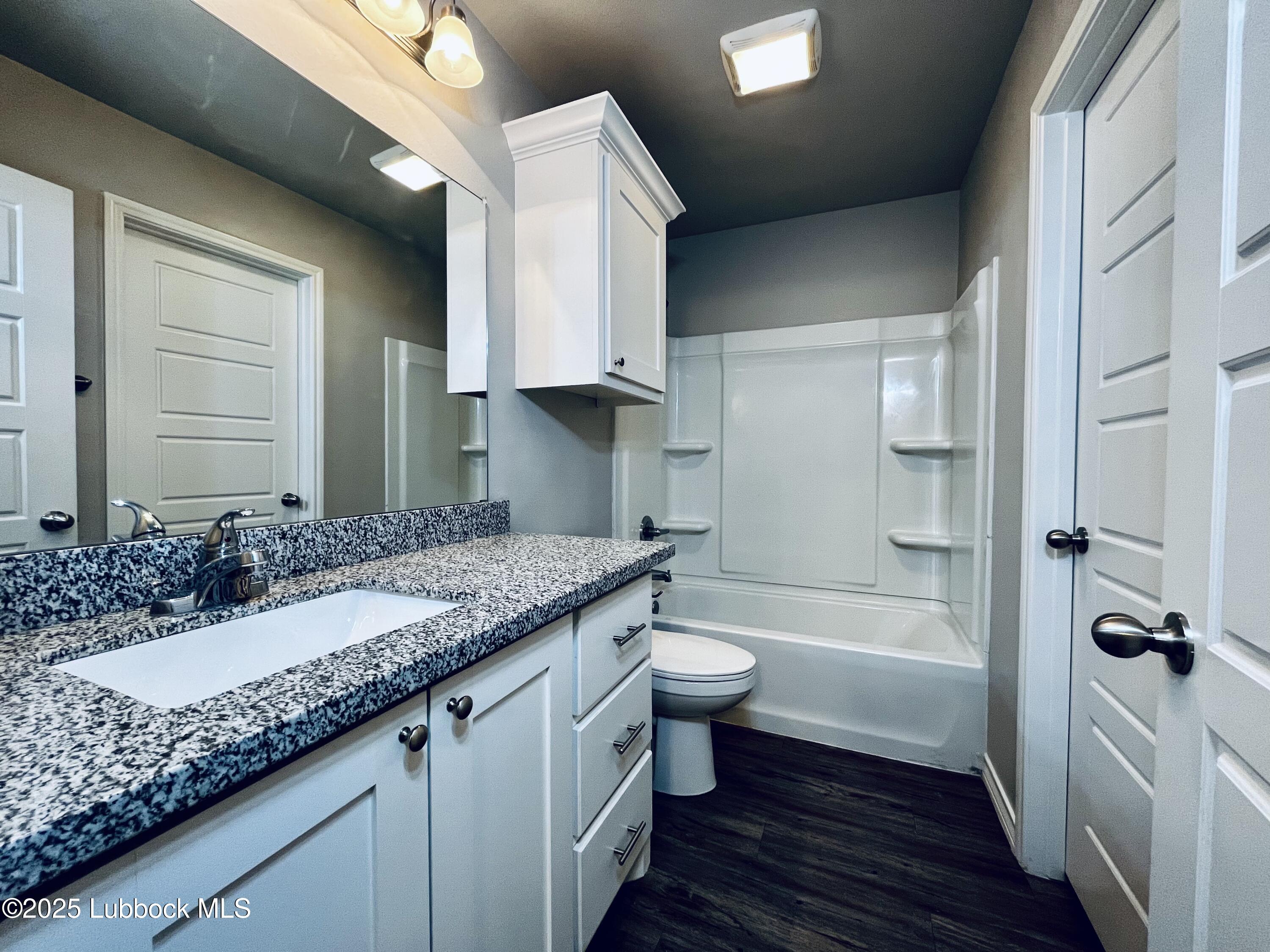 3404 25th Street, Unit 4 Lubbock, TX 79410 - Photo 13 of 15 a bathroom with a granite countertop sink toilet and shower
