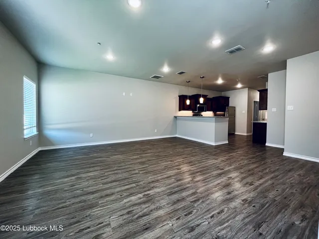 a view of a big room with wooden floor and a kitchen