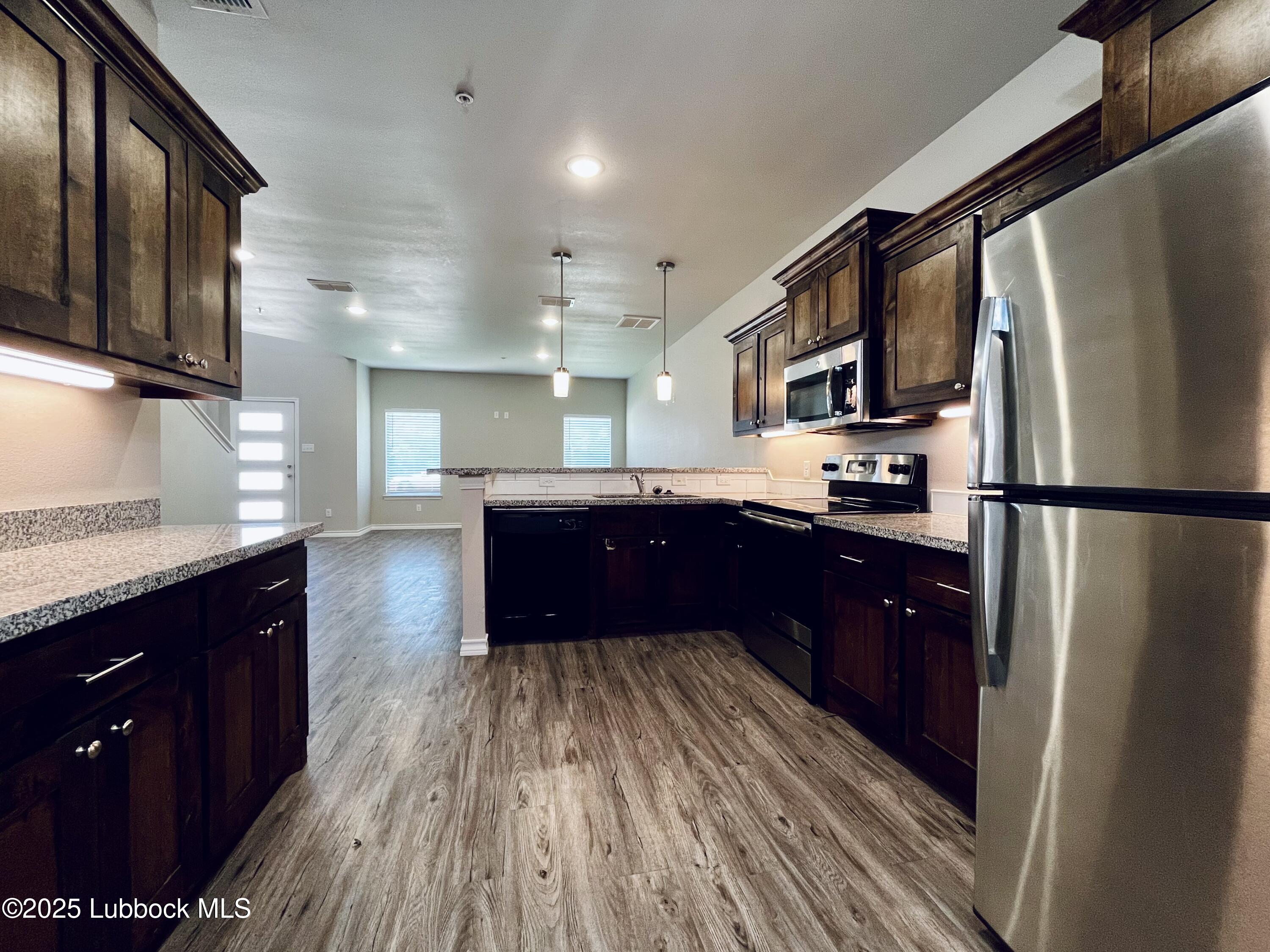 3404 25th Street, Unit 4 Lubbock, TX 79410 - Photo 5 of 15 a kitchen with wooden floors stainless steel appliances a sink and a window
