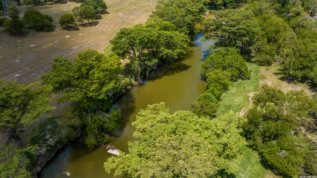 an aerial view of residential houses with outdoor space and trees all around