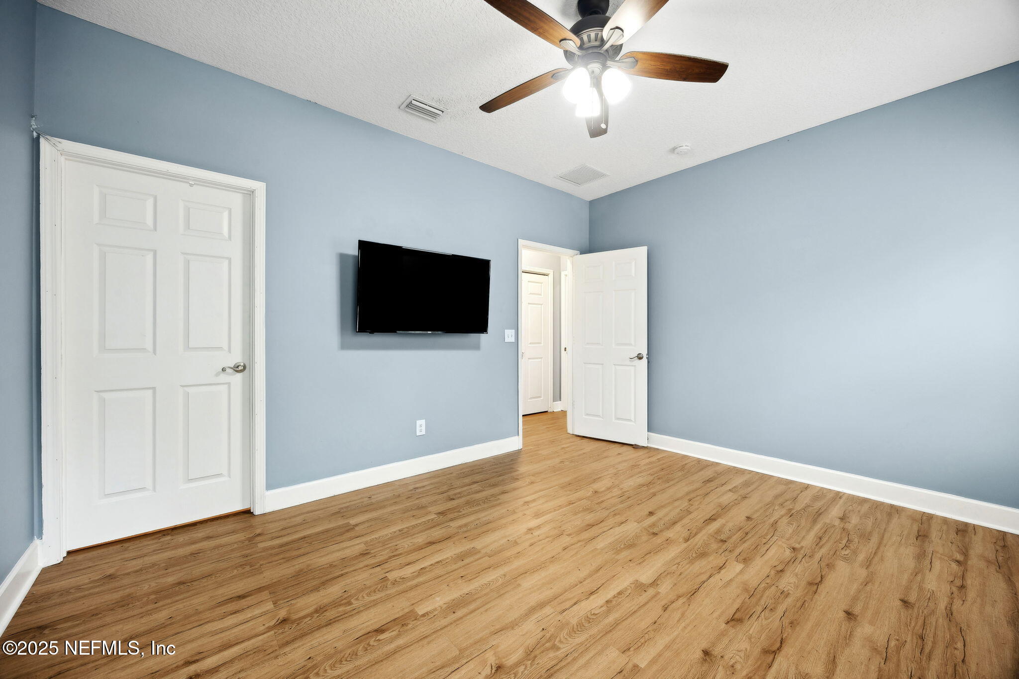85484 Miner Road Yulee, FL 32097 - Photo 21 of 38 a view of an empty room with wooden floor and a ceiling fan