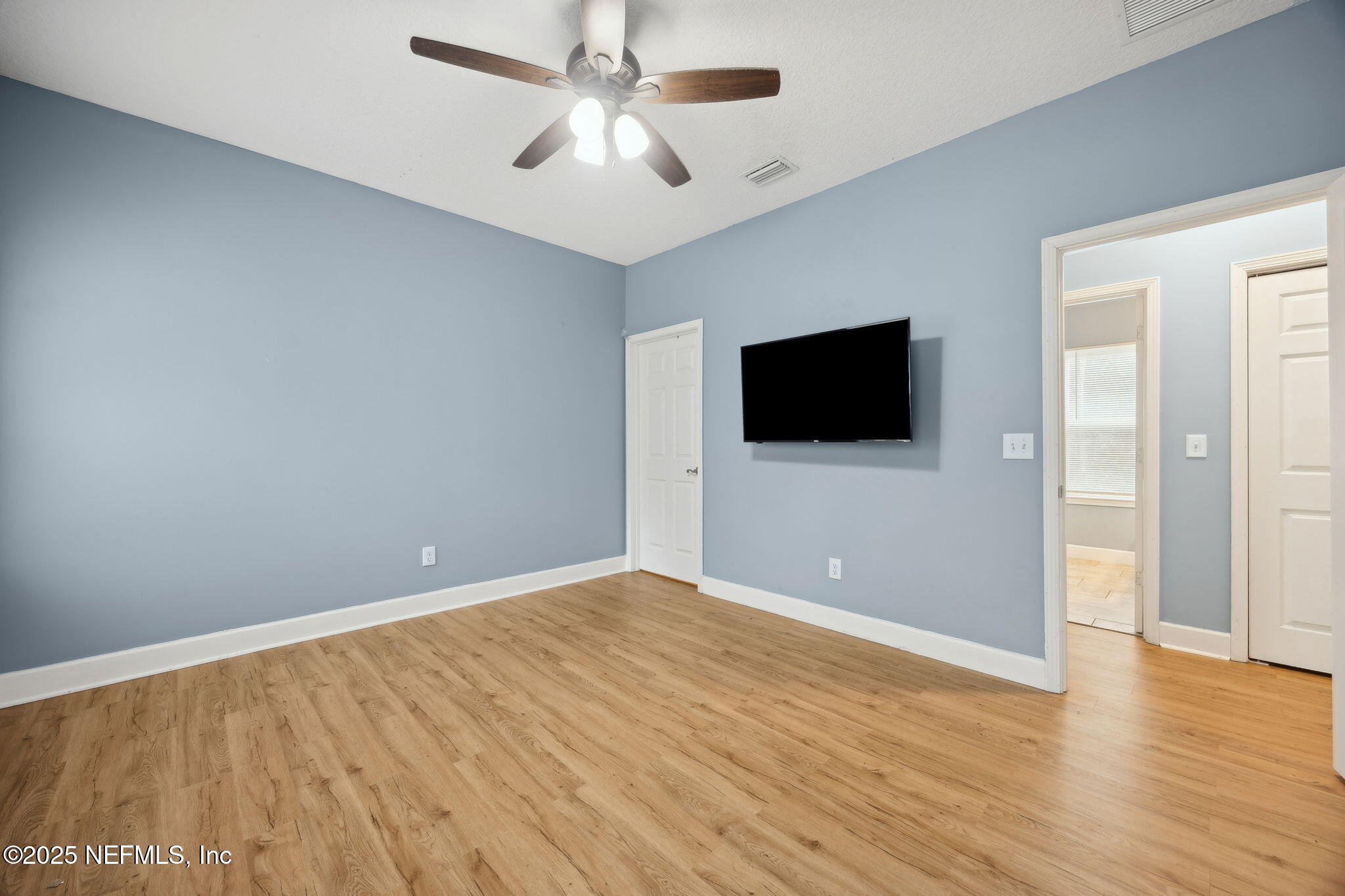 85484 Miner Road Yulee, FL 32097 - Photo 22 of 38 a view of an empty room with wooden floor and a flat screen tv