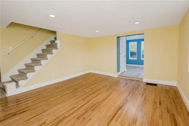 a view of an empty room with wooden floor and stairs