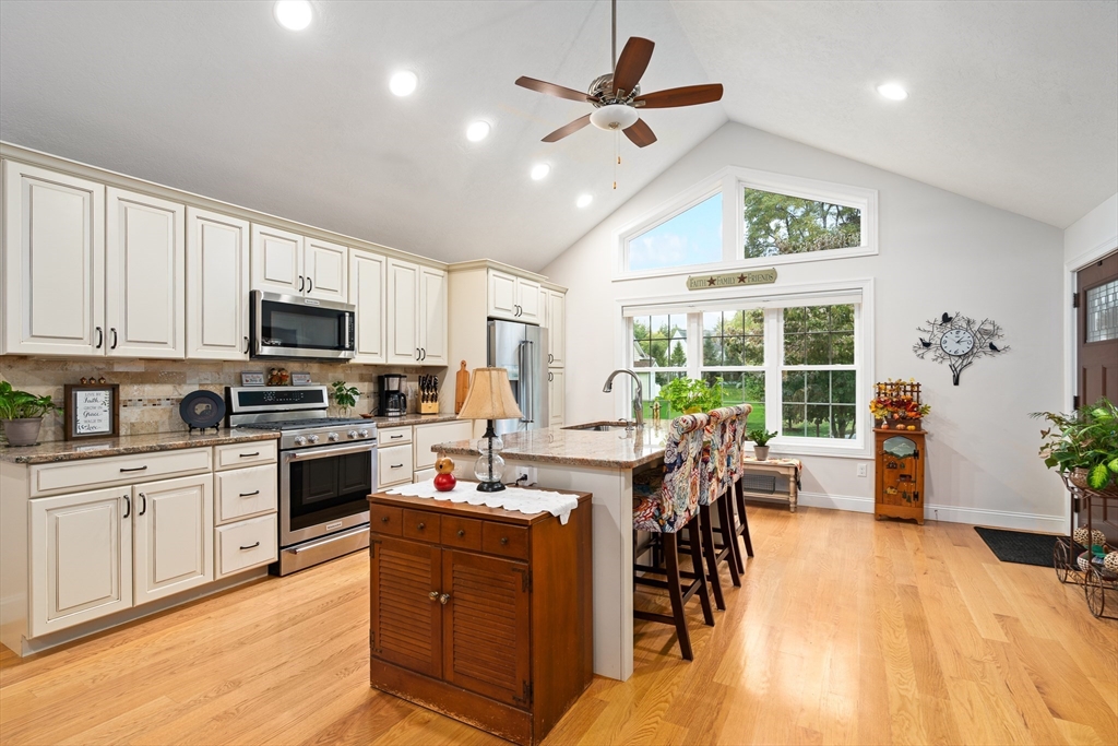 25 Paul Street Easthampton, MA 01027 - Photo 13 of 42 a open kitchen with stainless steel appliances granite countertop a stove top oven a sink dishwasher a dining table and chairs with wooden floor