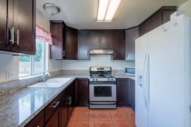 a kitchen with stainless steel appliances granite countertop a sink stove and refrigerator