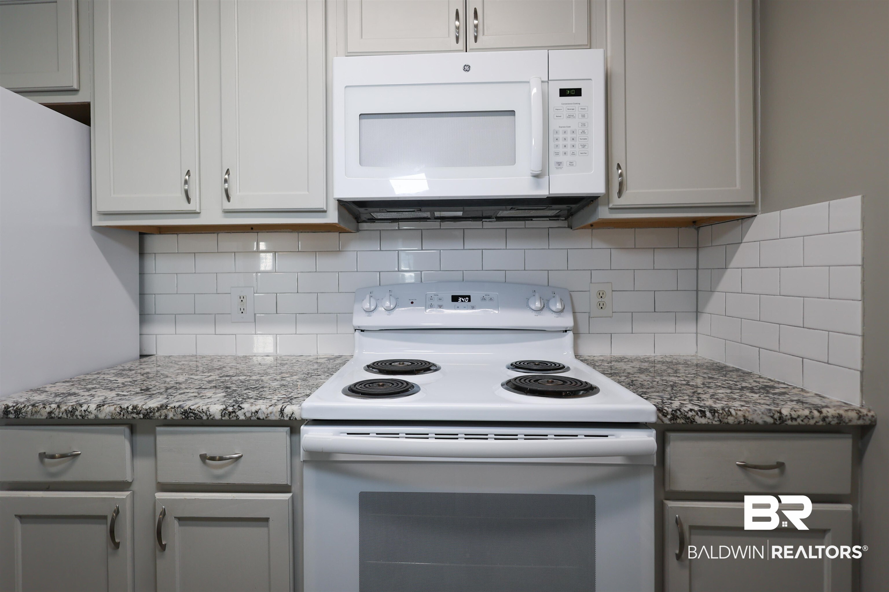 1517 Regency Road, Unit 125 Gulf Shores, AL 36542 - Photo 7 of 26 Kitchen with white appliances, light stone counters, gray cabinets, and decorative backsplash