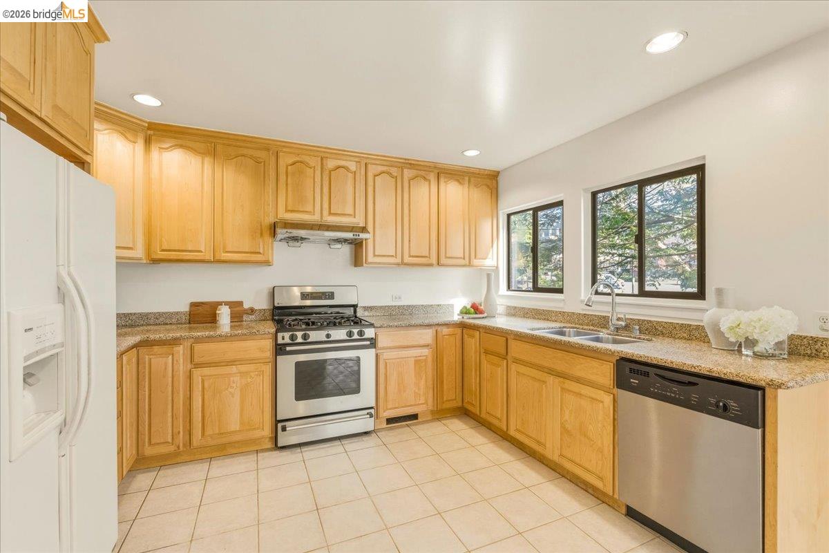 1408 Henry Street Berkeley, CA 94709 - Photo 11 of 28 Kitchen with stainless steel appliances, light wood finish cabinetry, light stone countertops, recessed lighting, and light tile patterned flooring