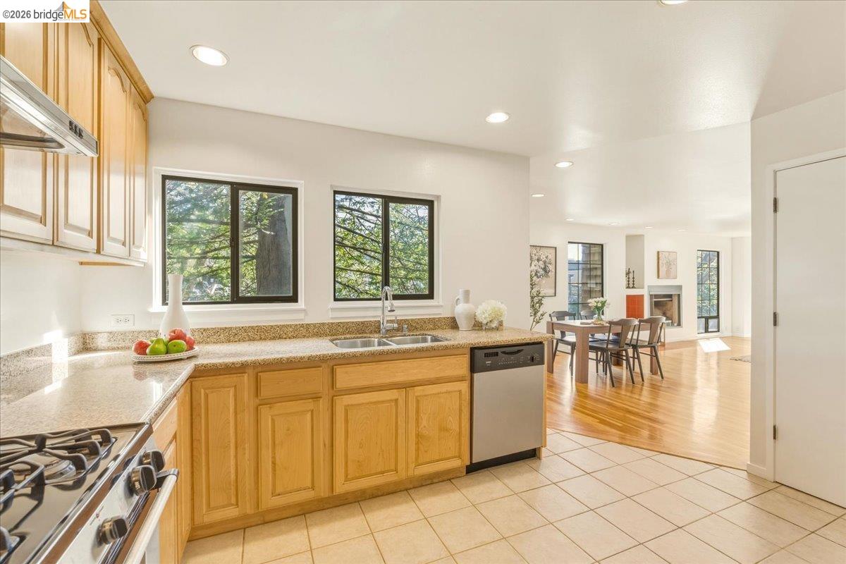 1408 Henry Street Berkeley, CA 94709 - Photo 12 of 28 Kitchen with light wood finish cabinets, stainless steel appliances, light tile patterned floors, light stone countertops, and a fireplace