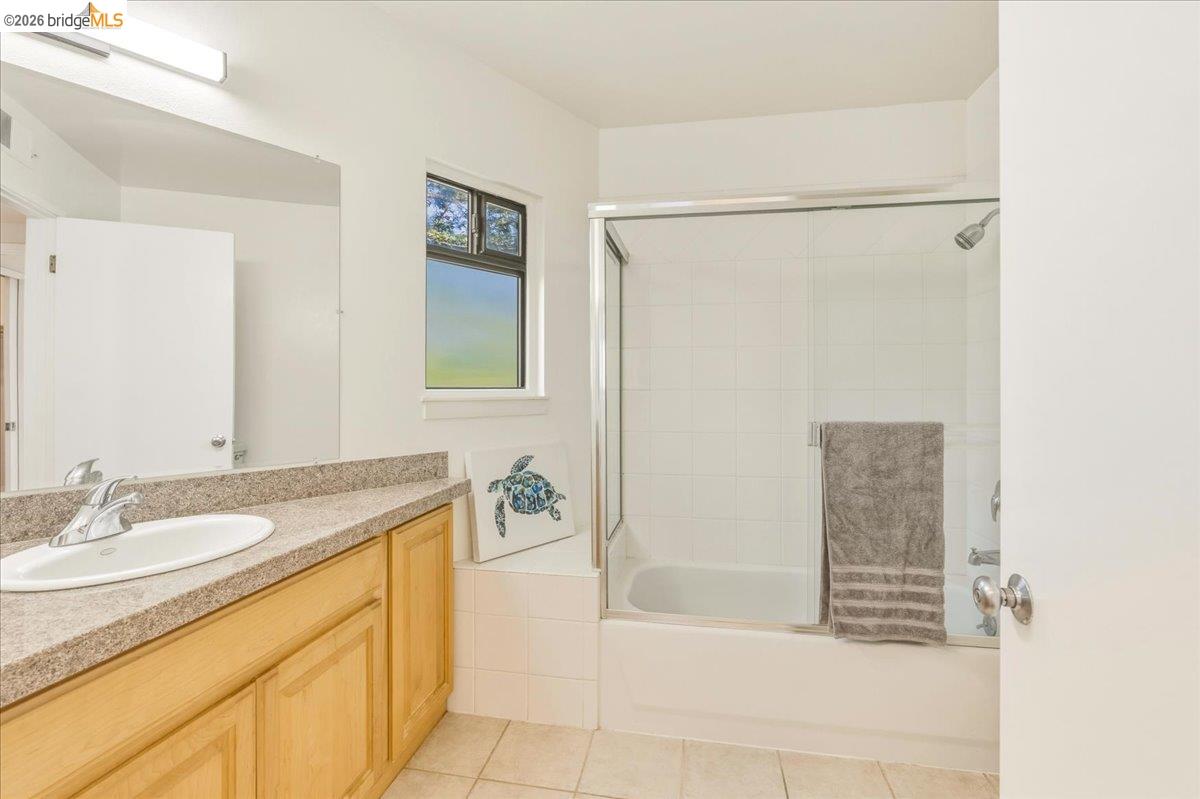 1408 Henry Street Berkeley, CA 94709 - Photo 23 of 28 Bathroom featuring vanity, light tile patterned floors, and bath / shower combo with glass door