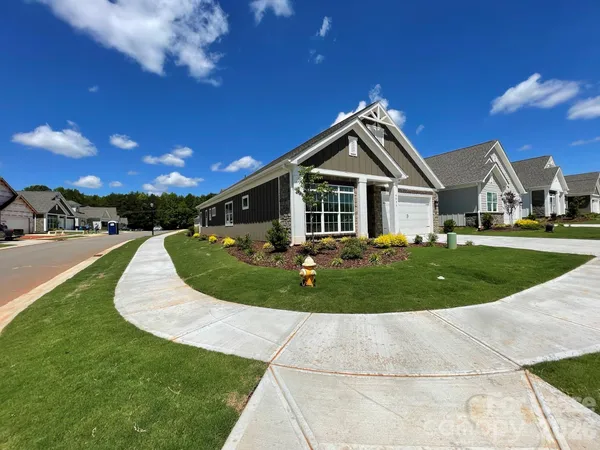 a view of a house with a big yard plants and large trees