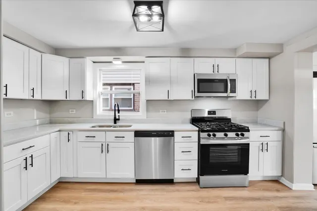 a kitchen with cabinets stainless steel appliances a sink and a wooden floor