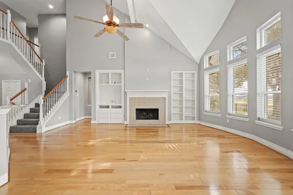 a view of an empty room with chandelier fan and fire place