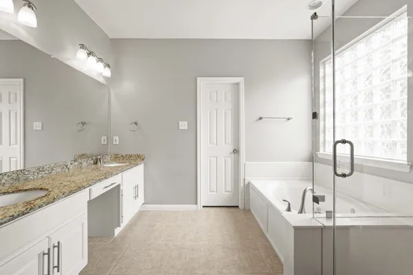 a spacious bathroom with a tub sink and mirror