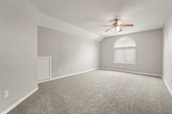 an empty room with windows and chandelier fan