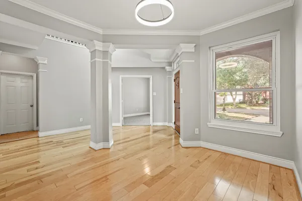 a view of empty room with wooden floor and fan