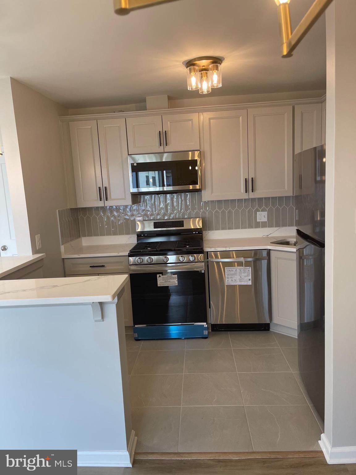 3142 Brinkley Road, Unit 6304 Temple Hills, MD 20748 - Photo 13 of 15 a kitchen with stainless steel appliances a stove a sink a refrigerator and a window