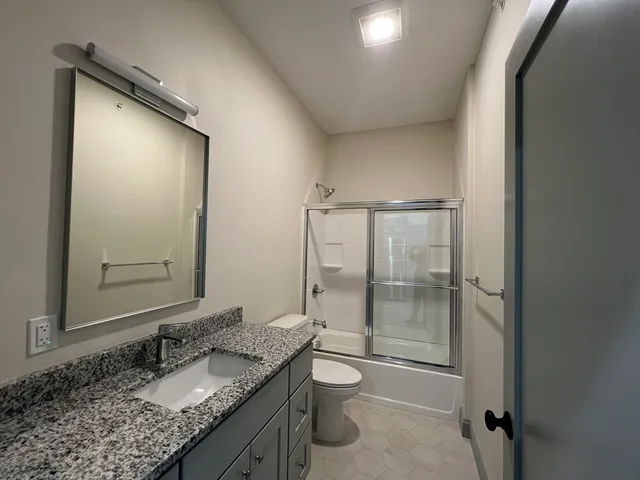 a bathroom with a granite countertop sink toilet and shower