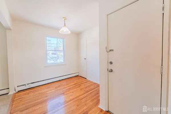 an empty room with wooden floor cabinet and windows