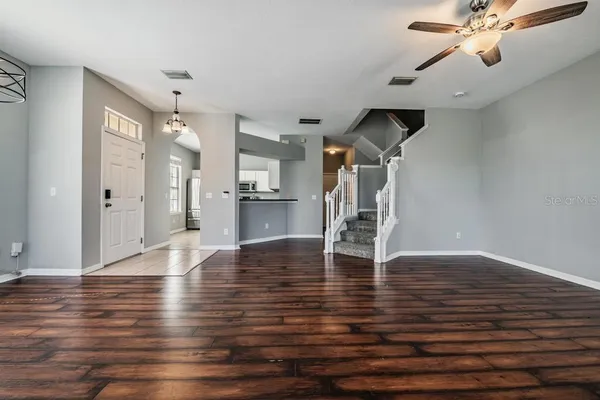 a view of empty room with wooden floor and fan